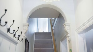 Eine Treppe mit weißer Brüstung, einem Chandelier und einem gerahmten Bild an der Wand.