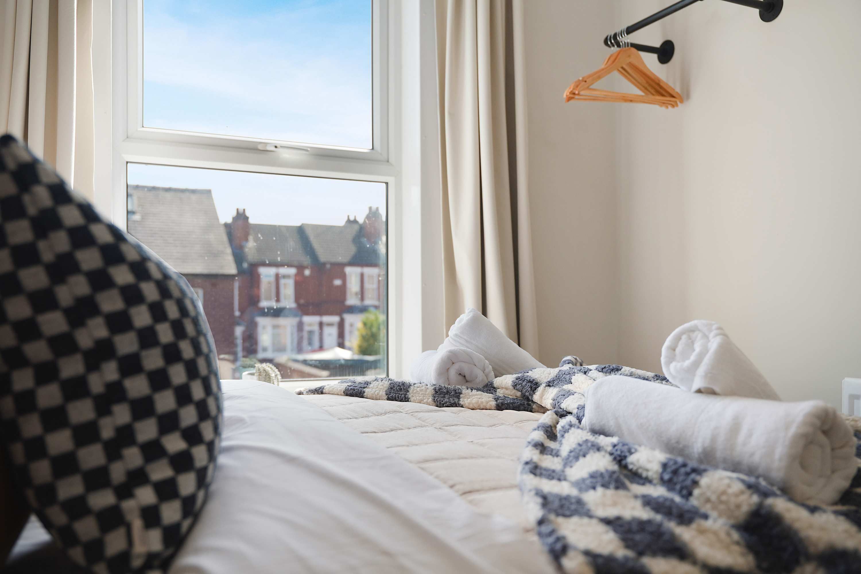Quarto com cama, janela e vista para casas lá fora.