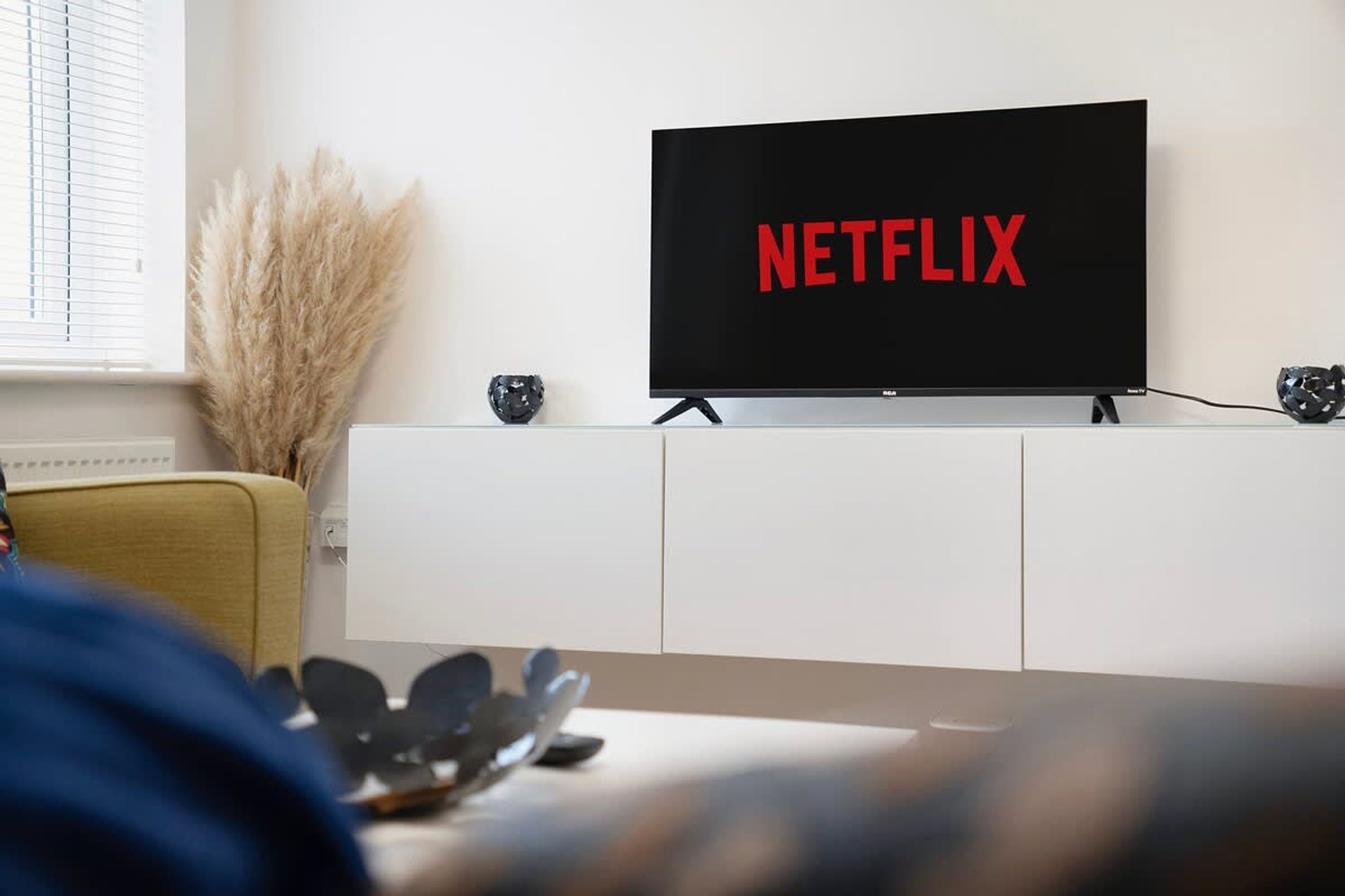 A television mounted on a white cabinet with the word 'NETFLIX' displayed on the screen.