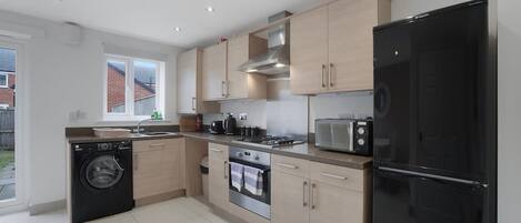 A modern kitchen with a washing machine, oven, microwave, and refrigerator.