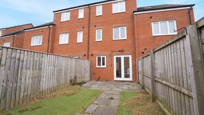 A residential building with a brick facade, a wooden fence, and a paved pathway leading to a door. - Spacious Retreat for 10 Perfect for Families (Durham)