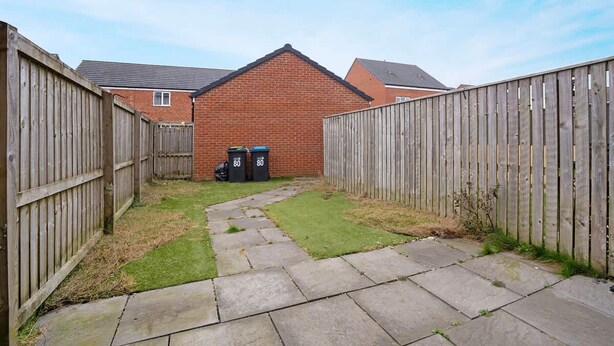 A backyard with a brick house, a wooden fence, and two trash bins. - Spacious Retreat for 10 Perfect for Families (Durham)