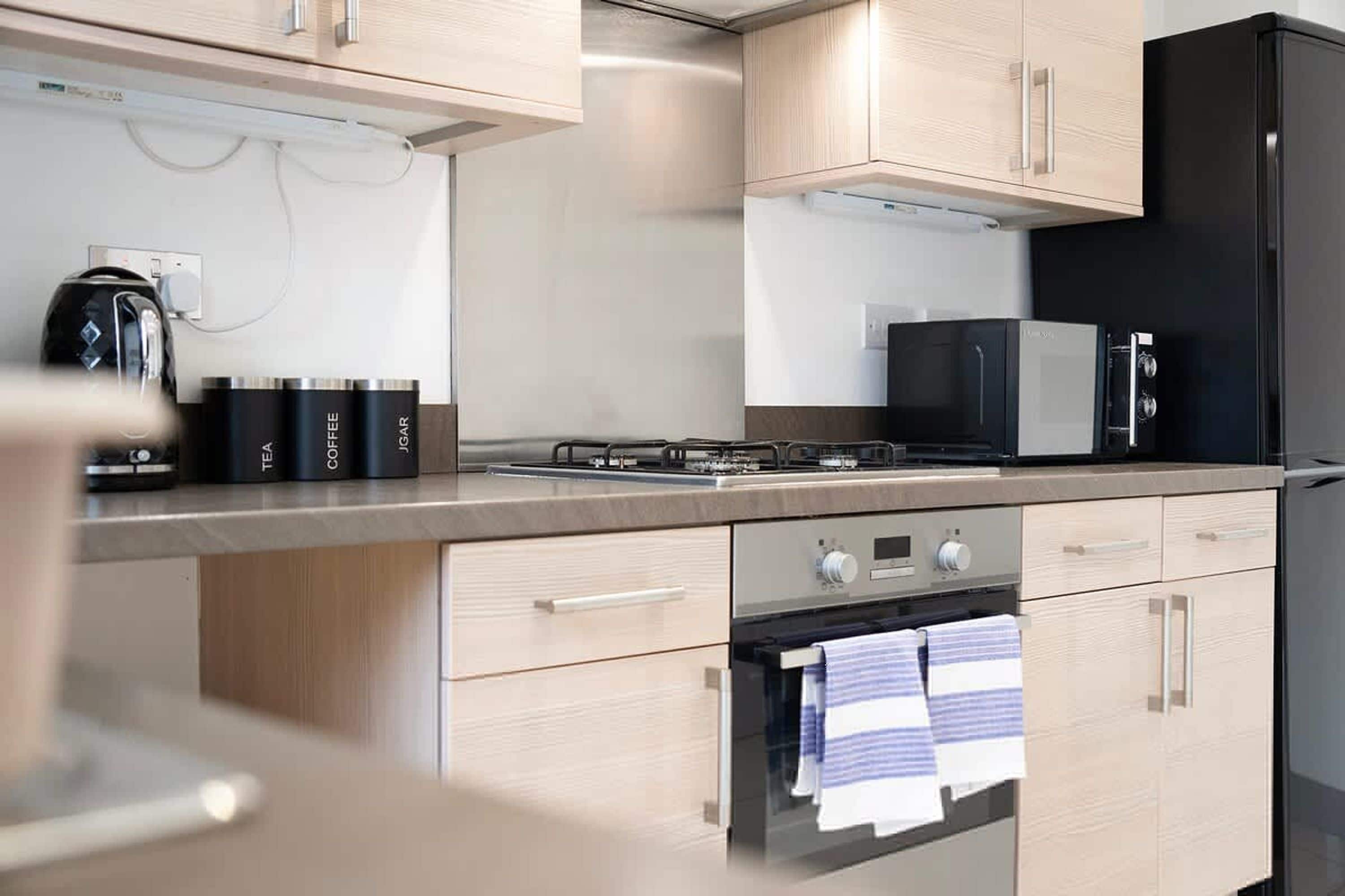 Une cuisine moderne dotée d’appareils électroménagers en acier inoxydable, de meubles en bois et d’un four encastré.