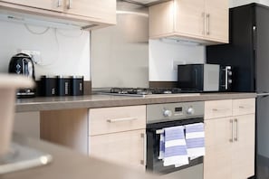Una cocina moderna con electrodomésticos de acero inoxidable, gabinetes de madera y un horno empotrado.