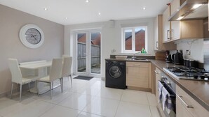 A modern kitchen with a dishwasher, stove, and dining area with chairs. - Spacious Retreat for 10 Perfect for Families (Durham)