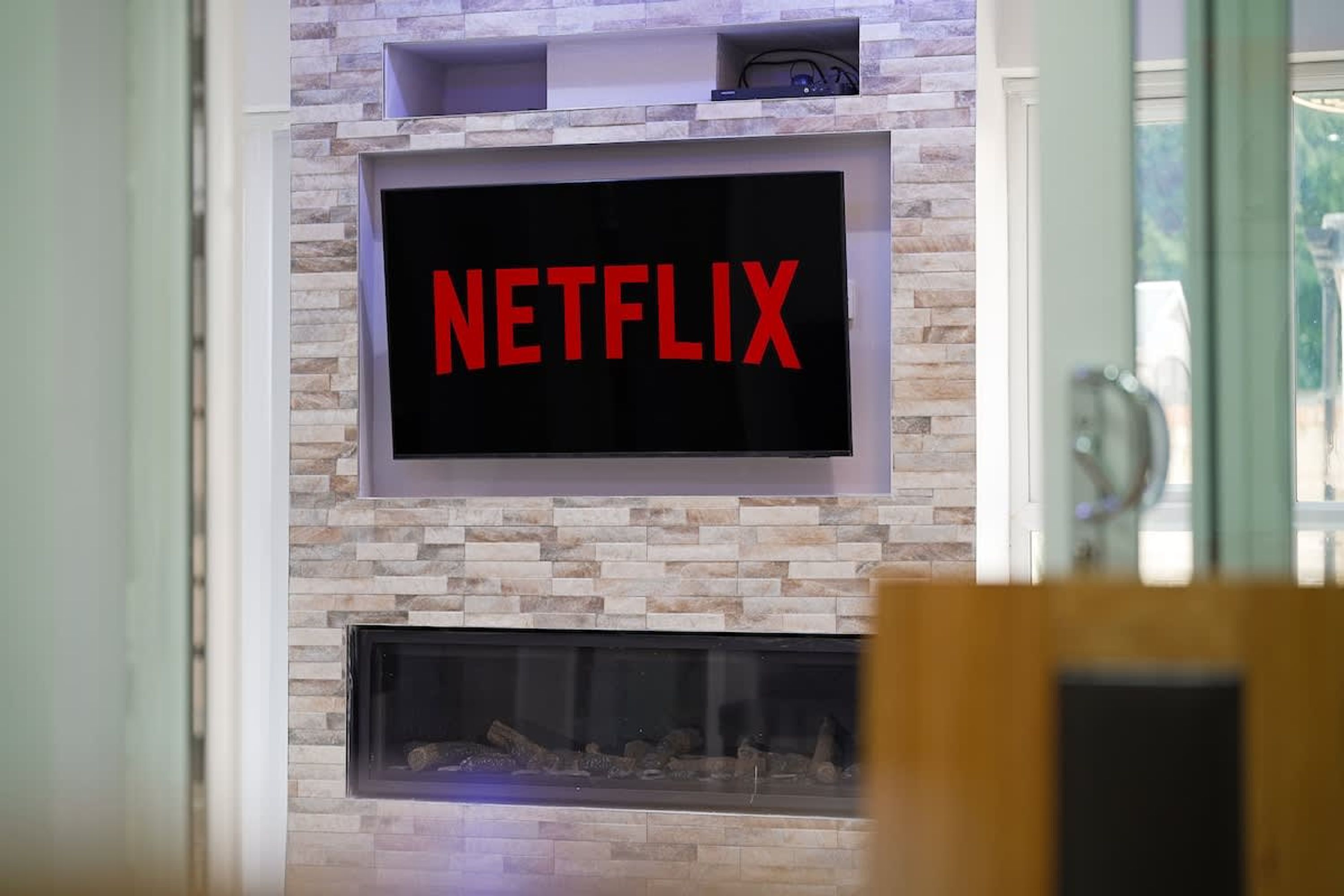 Un televisor de pantalla plana sujeto a una pared de piedra con el logotipo de Netflix.