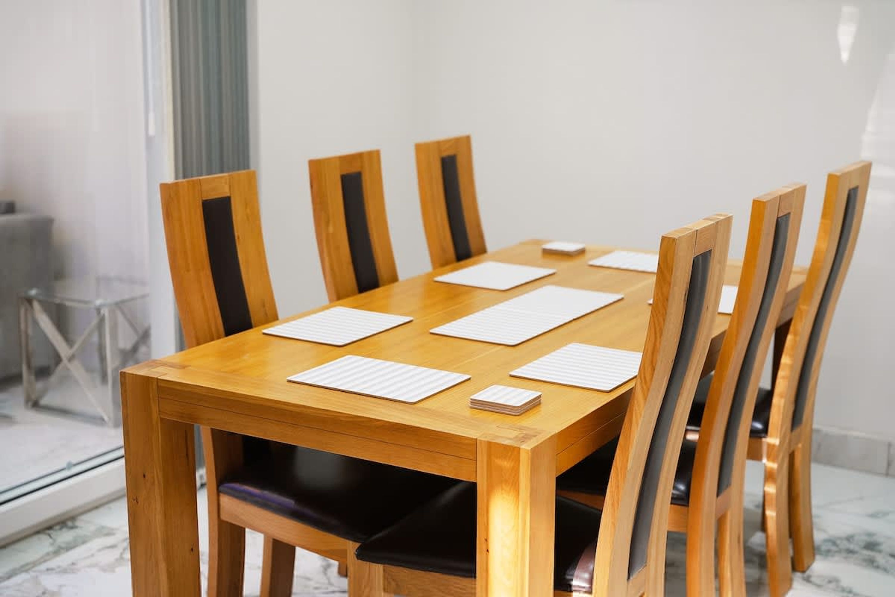 A wooden conference table with six chairs, a whiteboard, and a stack of papers.