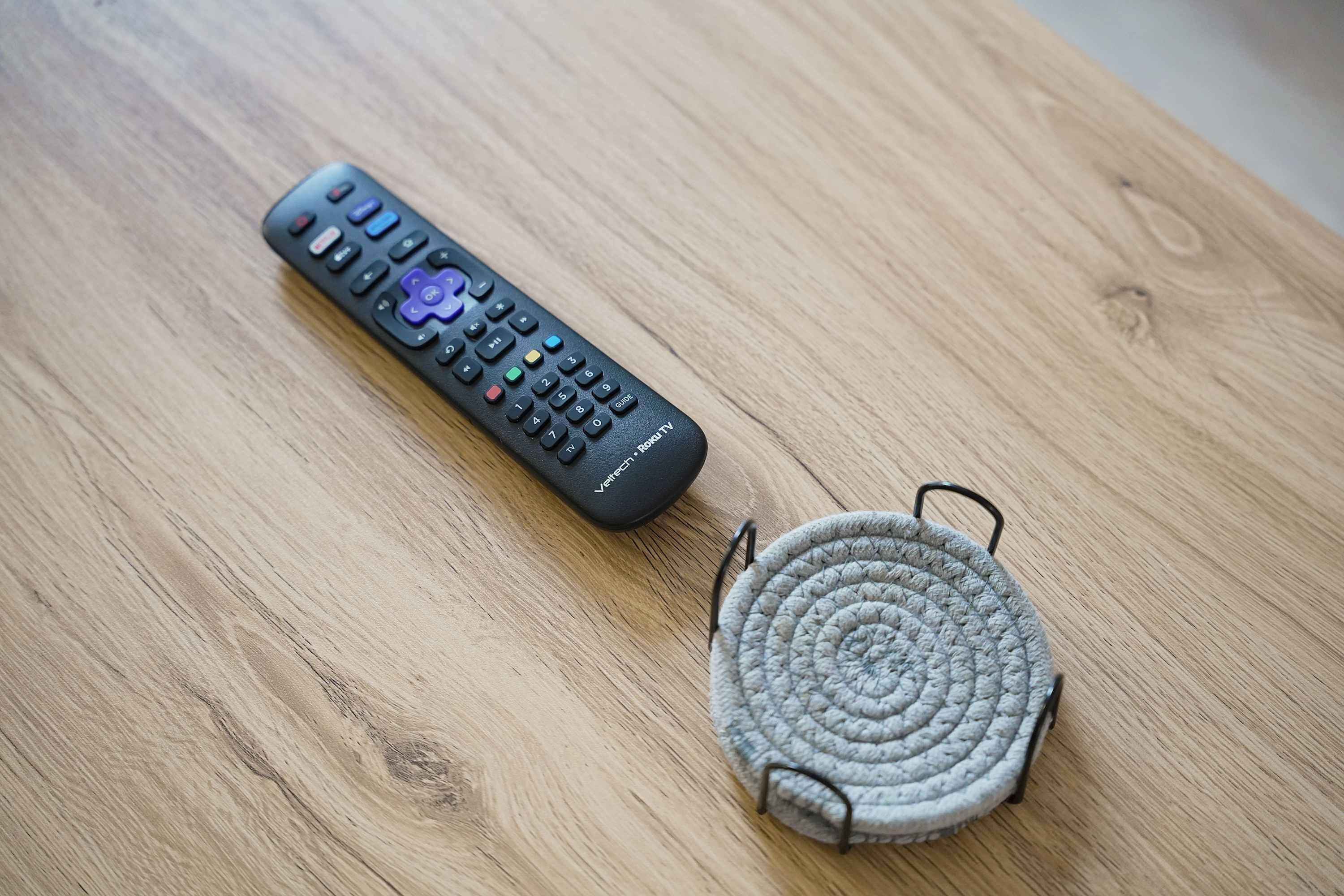 Un control remoto y un cable enrollado sobre una superficie de madera.