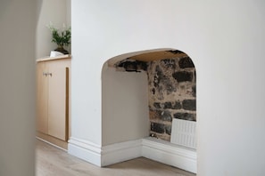 A corner of a room with a white wall, a wooden cabinet, and a brick wall.