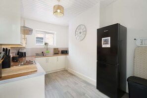 Una cocina moderna con un refrigerador negro, un reloj y una ventana con persianas.