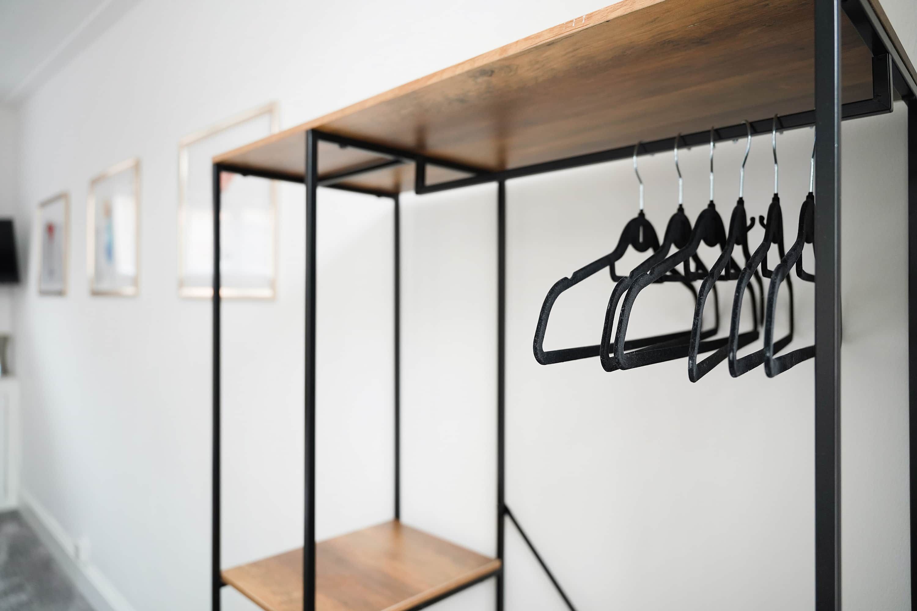 Una habitación con una repisa de madera y un perchero metálico.
