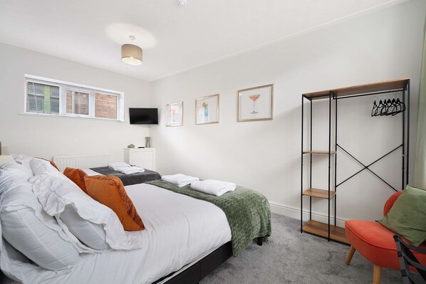 A bedroom with a bed, a TV, a wardrobe, and a chair.