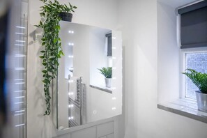 A bathroom with a large mirror, a potted plant, and a window with a view. - Spacious and Comfty 1 Bedroom Haven in Hartlepool (Hartlepool)