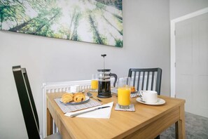 A breakfast table with croissants, a coffee maker, and glasses of orange juice. - Spacious and Comfty 1 Bedroom Haven in Hartlepool (Hartlepool)