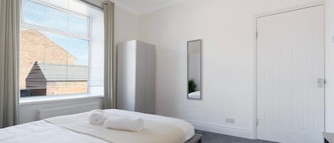 Un dormitorio con cama, armario, espejo y puerta.