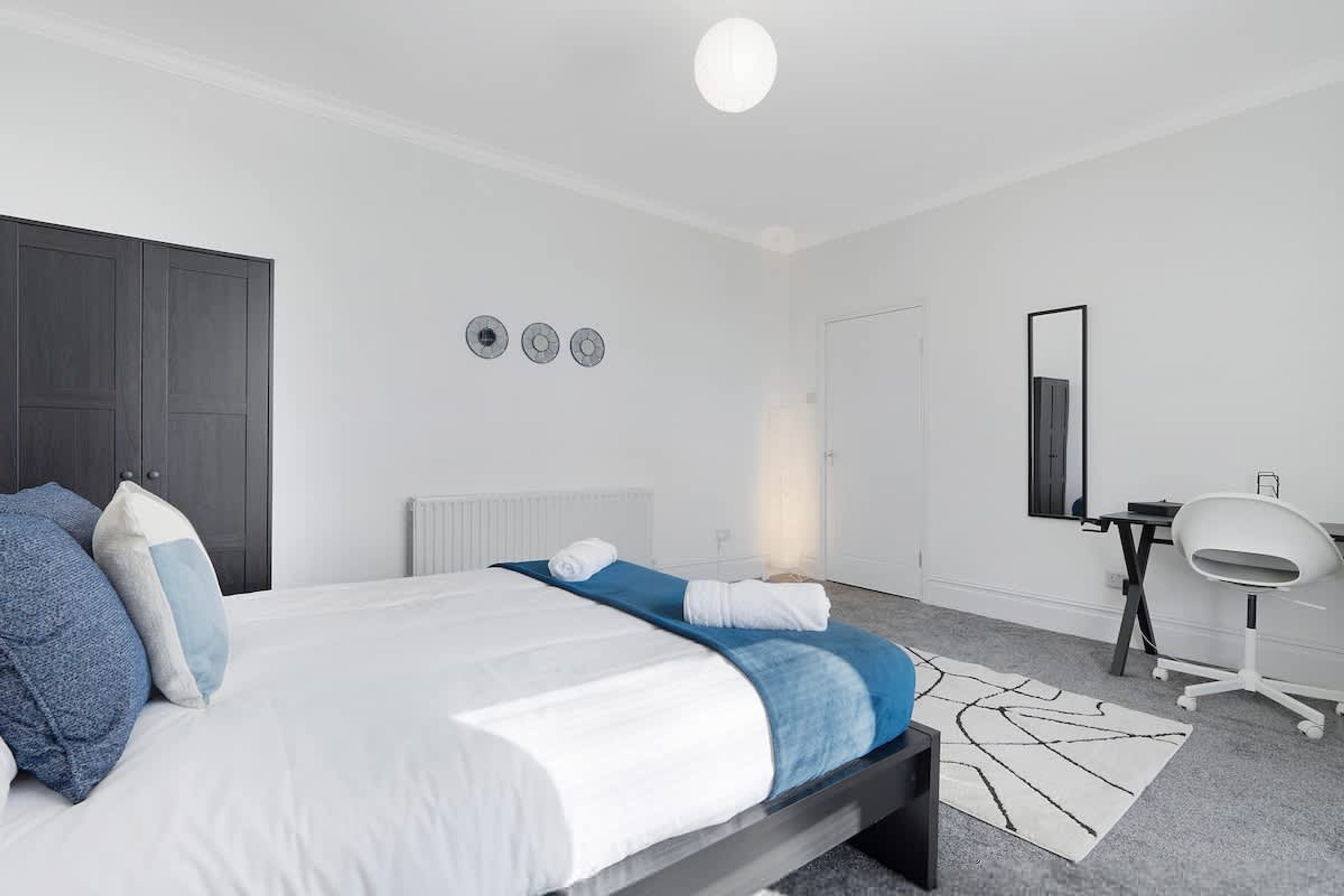 A modern bedroom with a bed, a desk, and a chair.