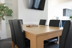 A conference room with a wooden table and black chairs, a flat-screen TV on the wall, and a potted plant. - 4BR on Durham Road Perfect For Large Groups (Stanley)
