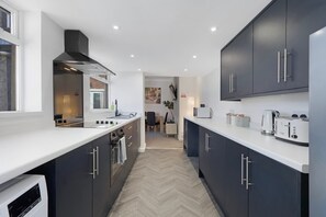 A modern kitchen with dark cabinets, a white countertop, and a herringbone floor pattern. - 4BR on Durham Road Perfect For Large Groups (Stanley)