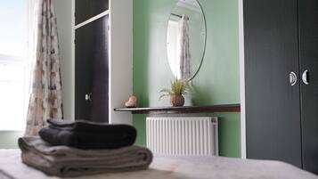 A bedroom with a bed, a radiator, a mirror, and a wardrobe.