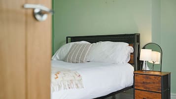 A bedroom with a bed, a bedside table with a lamp, and a wooden nightstand.