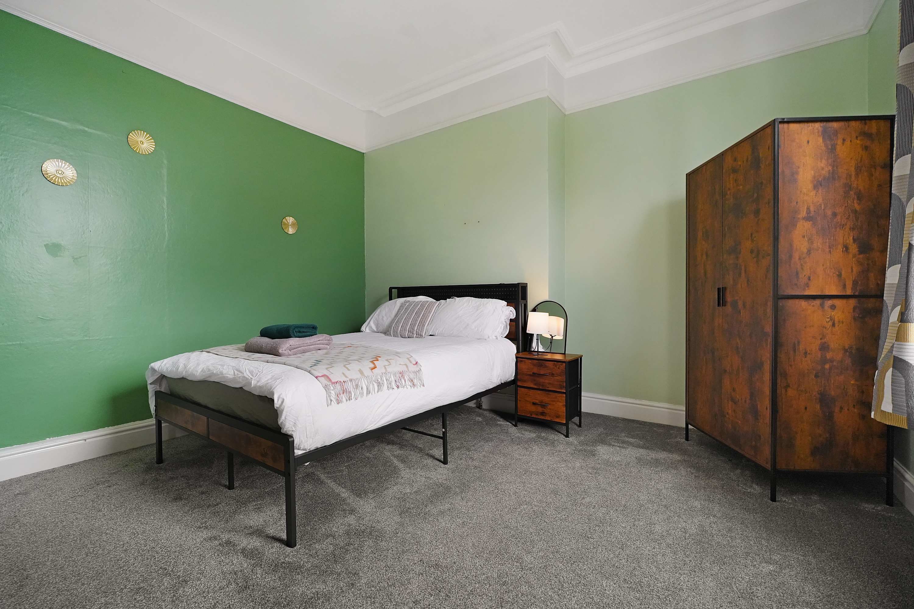 A bedroom with a bed, nightstand, and wardrobe.