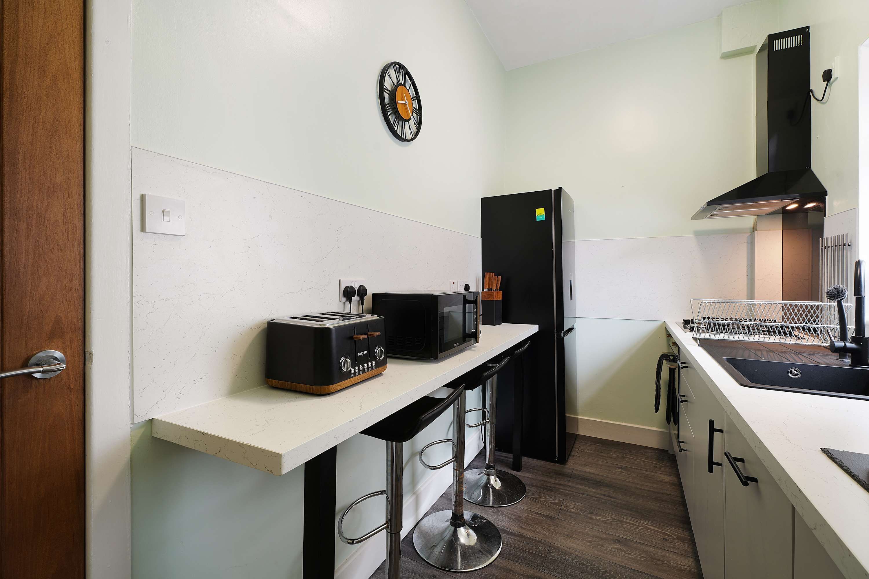 A modern kitchen with a white countertop, a black refrigerator, a toaster, and a microwave.