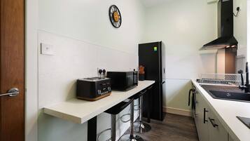A modern kitchen with a white countertop, a black refrigerator, a toaster, and a microwave.