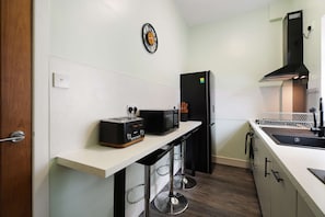 A modern kitchen with a white countertop, a black refrigerator, a toaster, and a microwave. - The Woodrouffe Retreat (Carlisle)