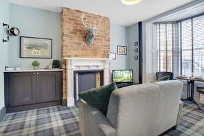 Ein Wohnzimmer mit Kamin, einer Couch, einem Fernseher und einer Ziegelwand.