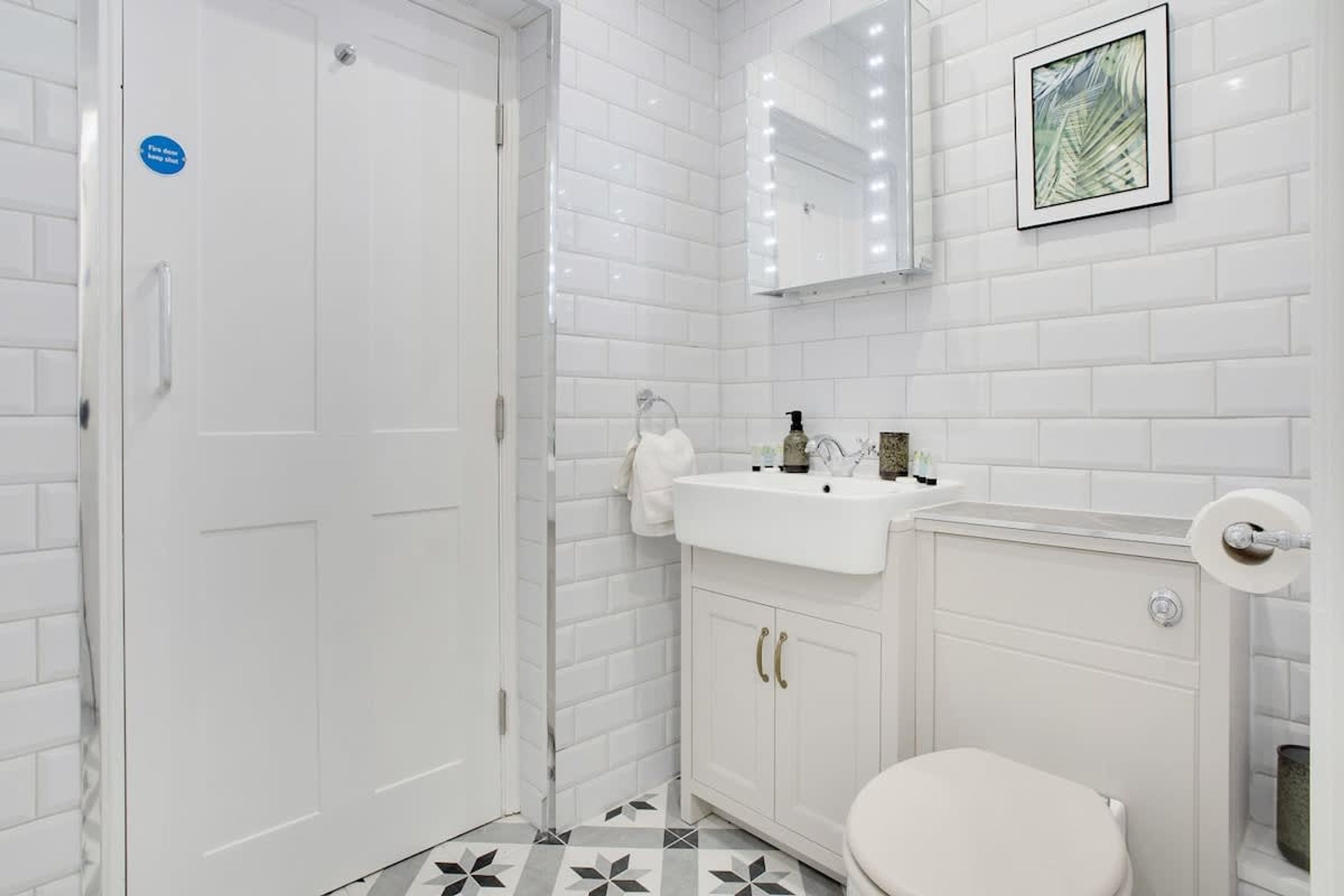 Un baño con lavamanos blanco, inodoro y zona de ducha.