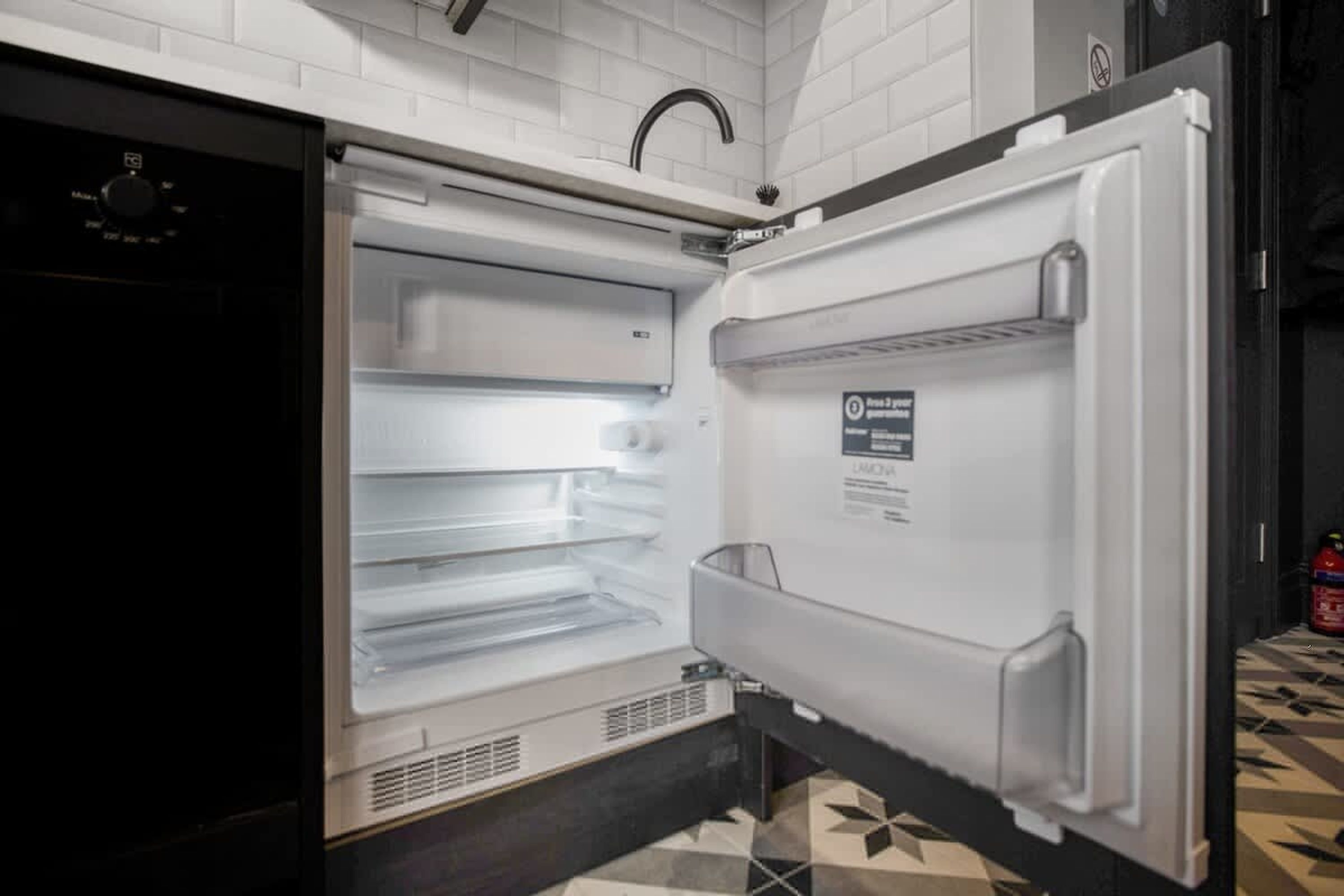 Ein offener Kühlschrank mit mehreren Ablagen und einem Wasserspender.