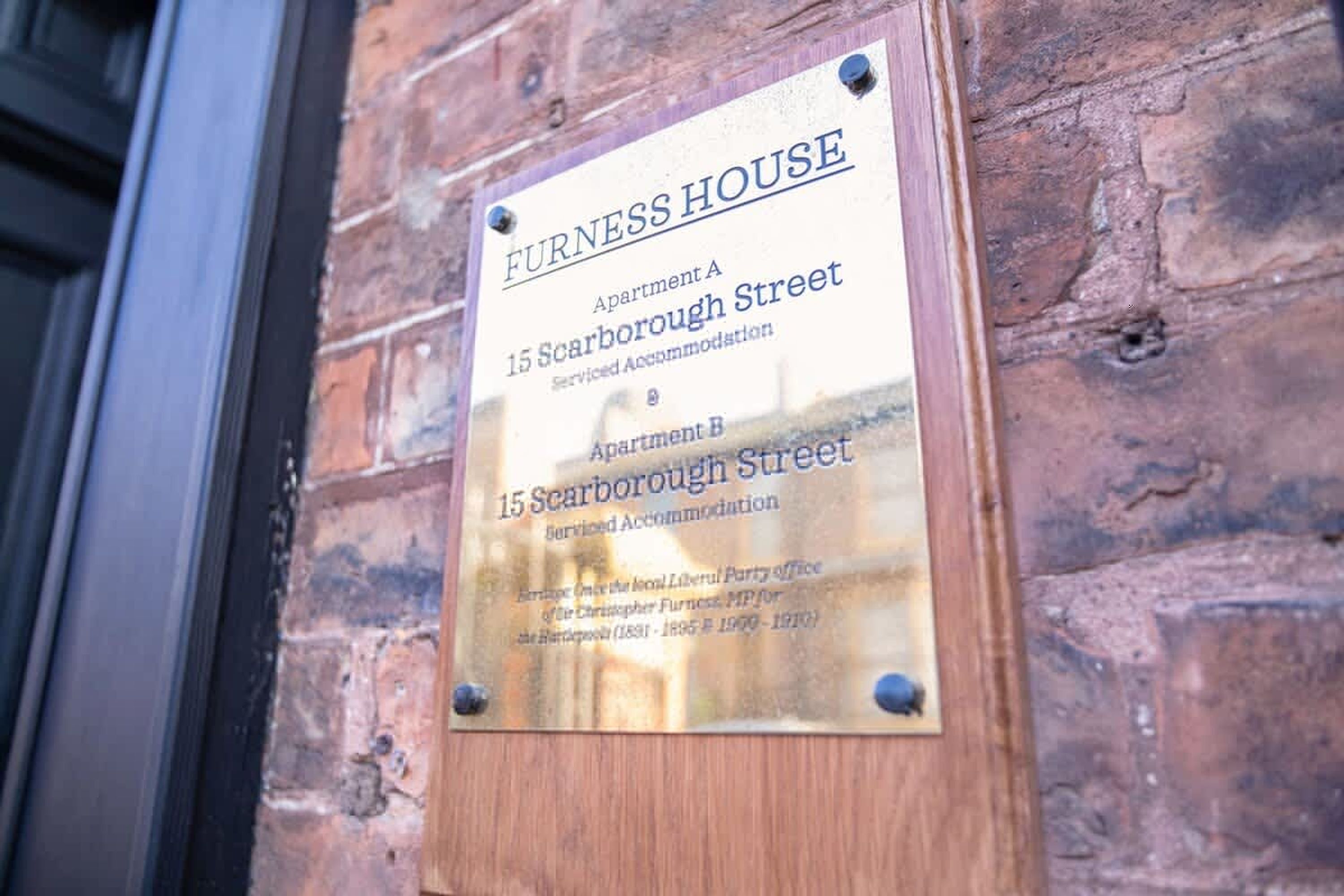 A plaque on a brick wall indicating 'Furness House' at '15 Scarborough Street' with 'Apartment A' and 'Apartment B' mentioned.