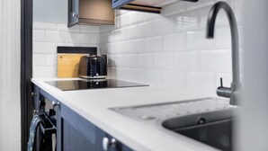 A modern kitchen with white tiles, a stainless steel sink, and a built-in oven. - Stylish 1BR Home Near Station by Stay With Us (Hartlepool)