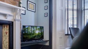 A living room with a fireplace, a television, and a window with blinds. - Stylish 1BR Home Near Station by Stay With Us (Hartlepool)