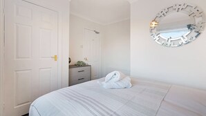 Habitació d'hotel amb un llit, una petita taula de nit, un mirall i una porta.