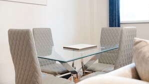 Un salón de conferencias con una mesa de vidrio y cuatro sillas tapizadas de color gris.