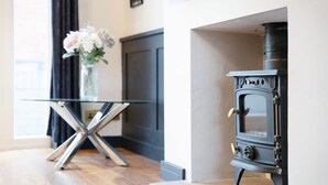 Una habitación con una mesa de vidrio, una estufa negra y un florero con flores.