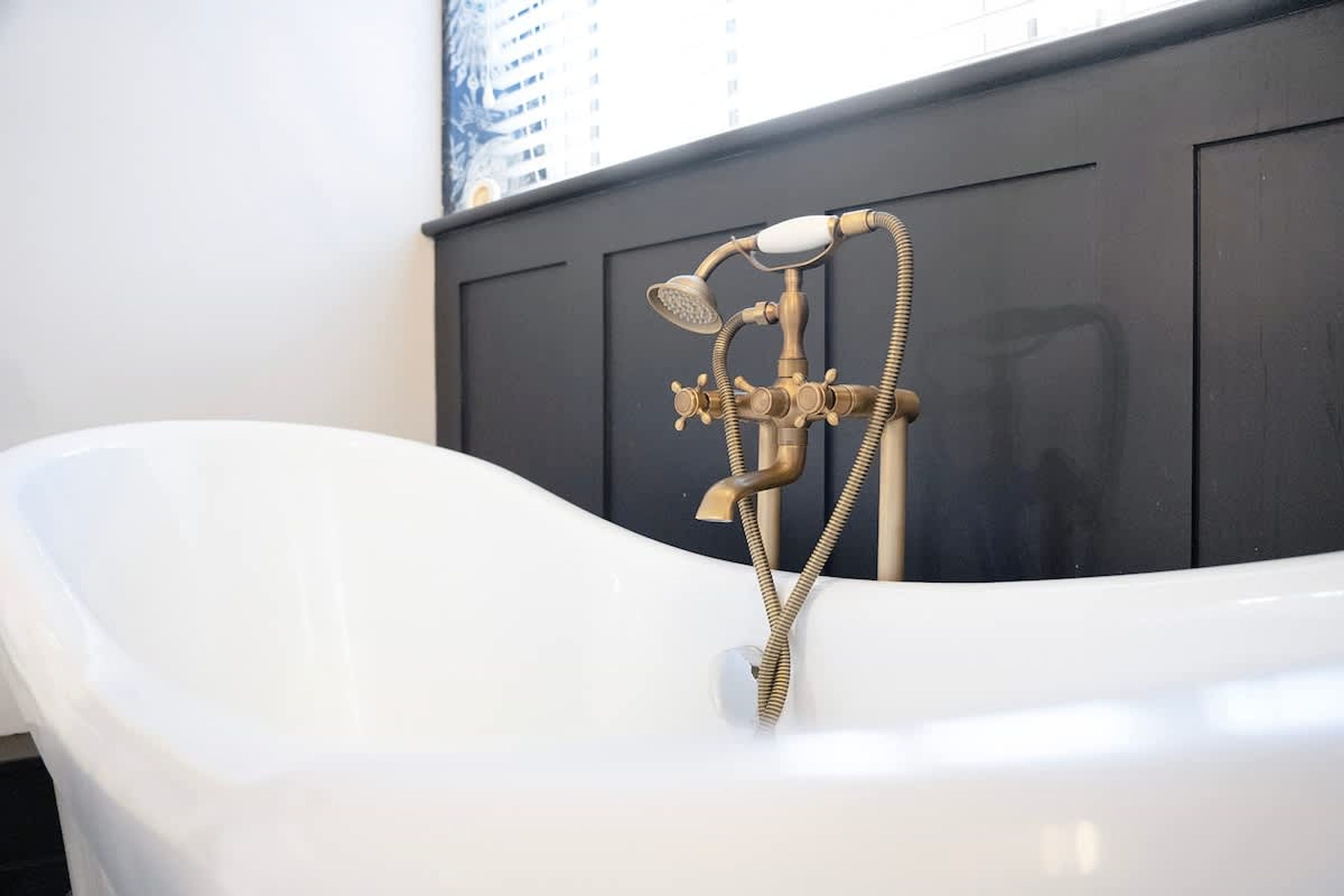 A white bathtub with a vintage-style shower head and hose.