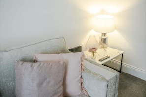 Et værelse med en sofa, en lampe og en fjernbetjening på et sofabord.