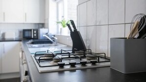 A modern kitchen with a gas stove, a knife block, and a plant. - Stylish 2BR House in Ashington by Stay With Us (Ashington)