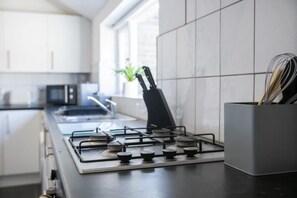 A modern kitchen with a gas stove, a knife block, and a plant. - Stylish 2BR House in Ashington by Stay With Us (Ashington)