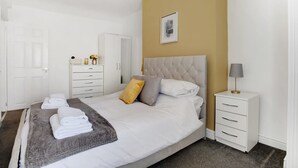 A hotel room with a bed, a bedside table, a wardrobe, and a door. - Stylish 2BR House in Ashington by Stay With Us (Ashington)