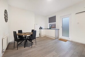 Une cuisine moderne avec des meubles blancs, un plan de travail noir et un petit îlot central.
