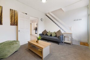 Un salon moderne avec un canapé, une table basse et un escalier.