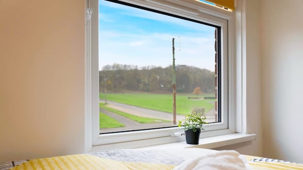 A room with a bed, a window with a view of a green field, and a potted plant on the windowsill. - Cosy 2BR Apartment Sleeps 4 by Stay With Us (Peterlee)