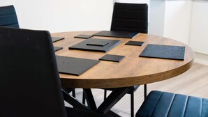 A round wooden table with black chairs, some black folders, and a smartphone on it. - Cosy 2BR Apartment Sleeps 4 by Stay With Us (Peterlee)