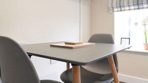 A modern office space with a table, chairs, a television mounted on the wall, and a window with a view of the outside. - Chic Flat Steps From Barnard Castle High Street (Barnard Castle)