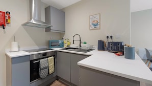 Una cocina moderna con gabinetes grises, una campana de acero inoxidable, un microondas, un fregadero y un tostador.