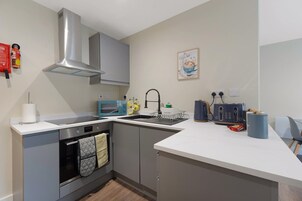 Una cocina moderna con gabinetes grises, una campana de acero inoxidable, un microondas, un fregadero y un tostador.