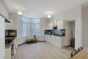 Una cocina moderna con armarios blancos, encimera negra y ventana con persianas.